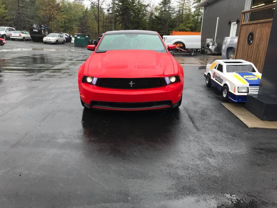 A red Mustang parked outside the JC AutoWorks shop